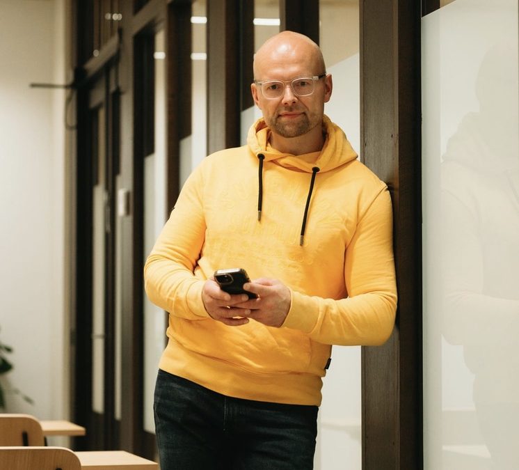 Turo Manninen keltaisessa hupparissa puhelin kädessään